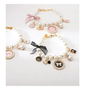 Pet pearl necklace detail showing elegant bow, crown, and perfume bottle pendants for small dogs.