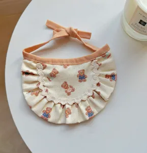 Pet bib detail view with cute bear pattern print, lace ruffle trim, and orange tie bow.