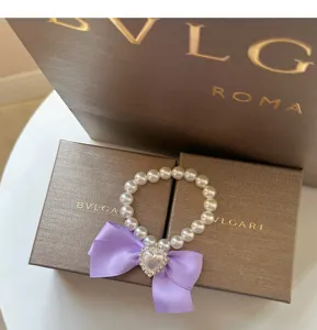 Nahaufnahme einer niedlichen Haustier-Perlenkette mit lila Schleife und Strass-Herz.
