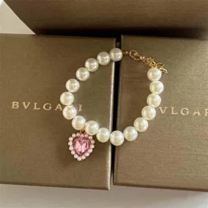 Pet pearl necklace with pink heart diamond pendant, elegant cat collar photography accessory.