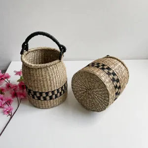 Detail shot of hand-woven seagrass storage basket featuring black geometric pattern and handle.