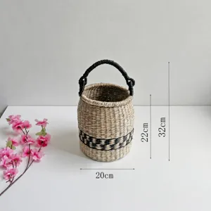 Handmade woven seagrass basket with black handle and pattern detail, natural home decor.