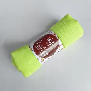 Detail view of the rolled light green crinkle cotton linen scarf with packaging band.