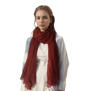 Solid color crinkled cotton linen scarf with tassel edge, worn by a model in front view.