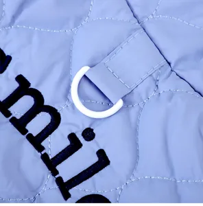 Close-up detail of light blue quilted pet cat vest with black embroidery and traction D-ring.