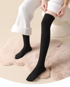 Nahaufnahme von warmen schwarzen Damen Overknee Socken in einer gemütlichen Umgebung.
