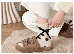 Gros plan détaillé de chaussettes moelleuses en peluche avec un joli nœud noir et motif.