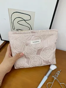Close-up of pink embossed rose cosmetic bag detail, showing fine embroidered texture.