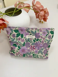 Detail view of retro french jacquard cosmetic bag with purple floral pattern and cute cloth label.