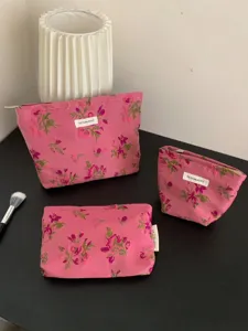 Pink floral embroidered cosmetic bag detail featuring exquisite stitching, zipper, and woven label.