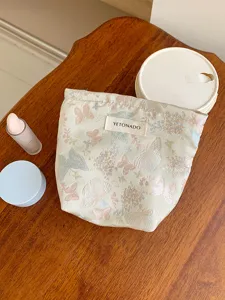 Close-up of the elegant jacquard cosmetic pouch featuring delicate butterfly patterns and fabric tag.