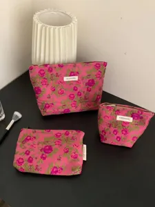Floral print makeup bag set of three canvas cosmetic pouches with zipper and white brand label.