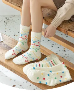 Dettaglio calzini pile corallo bianco con morbida texture peluche e motivi ondulati colorati invernali.
