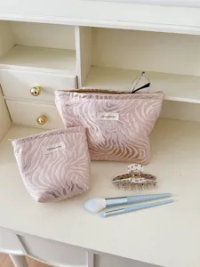 Detail view of pink striped embossed cosmetic makeup bag set, portable travel storage pouch.