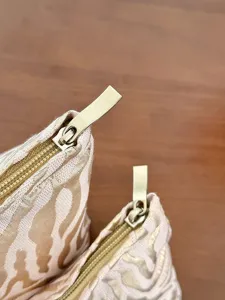 Close-up detail of stylish striped embossed cosmetic makeup bag zipper and texture.