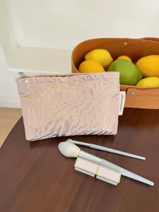Detail view of pink cosmetic bag with silver zebra embossing, zipper closure, and side tag.