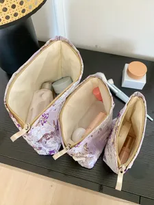 Set of 3 purple floral embroidered cosmetic bags with zip closure for travel storage.
