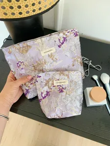 Detail showcase of purple floral embroidered cosmetic bags set, displaying fine fabric texture.
