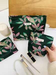 Detailed view of embroidered green floral cosmetic bag, portable makeup pouch and organizer.