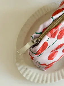 Close-up detail of cute cherry pattern jacquard cosmetic pouch with metal zipper pull.