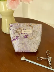Detail view of the purple floral brocade cosmetic storage bag featuring elegant gold embroidery.