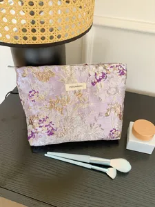 Detailed view of the elegant purple floral embroidered cosmetic bag showcasing delicate texture.