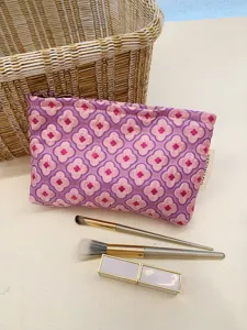 Close-up detail of the pink floral jacquard cosmetic pouch fabric, styled with makeup brushes.