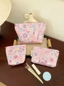 Detailed view of a 3-piece floral cosmetic bag set with brand label, perfect for travel.