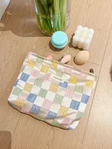 Close-up detail shot of the pastel checkered cosmetic pouch with cute floral embroidery.