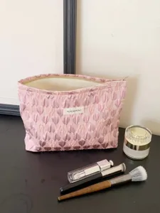 Detailed view of pink heart quilted cosmetic bag, portable makeup pouch shown on dark table.