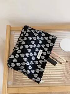 Black cosmetic bag featuring silver heart pattern, stylish travel makeup pouch organizer.