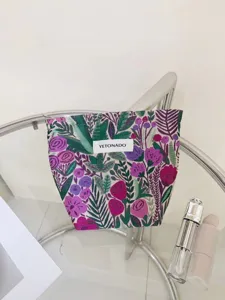 Embroidered floral cosmetic pouch detail, woven YETONADO label, portable travel storage bag.