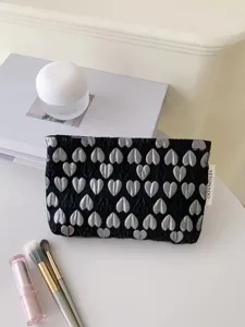 Detailed close-up of a black cosmetic bag featuring elegant silver 3D heart jacquard patterns.