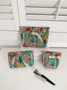 Detailed close-up view of embroidered floral cosmetic travel bags set with makeup brushes.