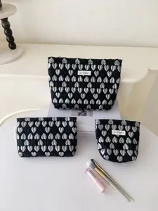 Detail view of stylish black cosmetic bags set with silver heart pattern and portable design.