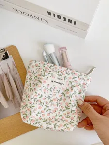 Detailed view of the floral cotton cosmetic pouch showing fabric texture, zipper, and brand tag.