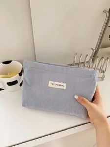 Close-up detail of the light blue corduroy cosmetic bag, showing soft texture and fabric label.