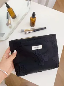 Sac cosmetique noir avec broderie de noeud, pochette de maquillage et rangement de toilette.