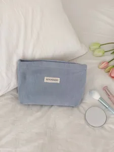Blue corduroy cosmetic bag detail showing soft textured fabric and custom brand label design.