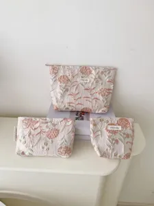 Detail shot of floral cosmetic travel organizer pouches set, elegant embroidery design.