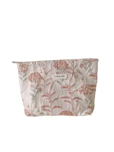 Detail view of the floral embroidered cosmetic pouch with zipper and woven logo tag.