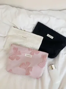 Vue détaillée de trousses de maquillage rétro à nœuds teints en fil en rose, blanc et noir.