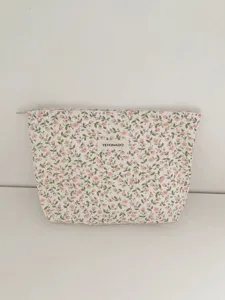 Close-up detail of the floral cosmetic bag fabric, showing vintage print and brand label.