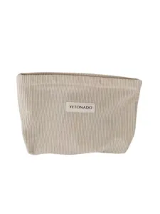 Close up of beige corduroy makeup pouch, soft fabric texture, portable daily organizer bag.