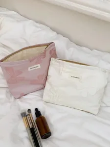 Vue détaillée de la trousse de maquillage nœud rétro, texture tissée et fermeture zippée pratique.