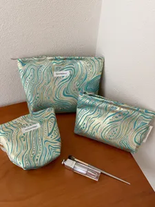 Three-piece blue and gold jacquard cosmetic bag set, portable travel makeup storage pouch.