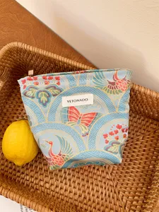 Close-up detail of the vintage crane and butterfly print cosmetic bag with woven label.