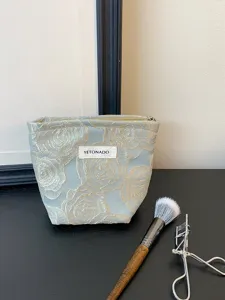 Embossed rose pattern makeup bag detail view, showing exquisite golden floral embroidery texture.