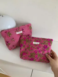 Detailed view of pink floral cosmetic storage bag with woven label and zipper closure.