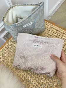 Embroidered rose cosmetic bag detail, elegant storage pouch with zipper and custom brand label.